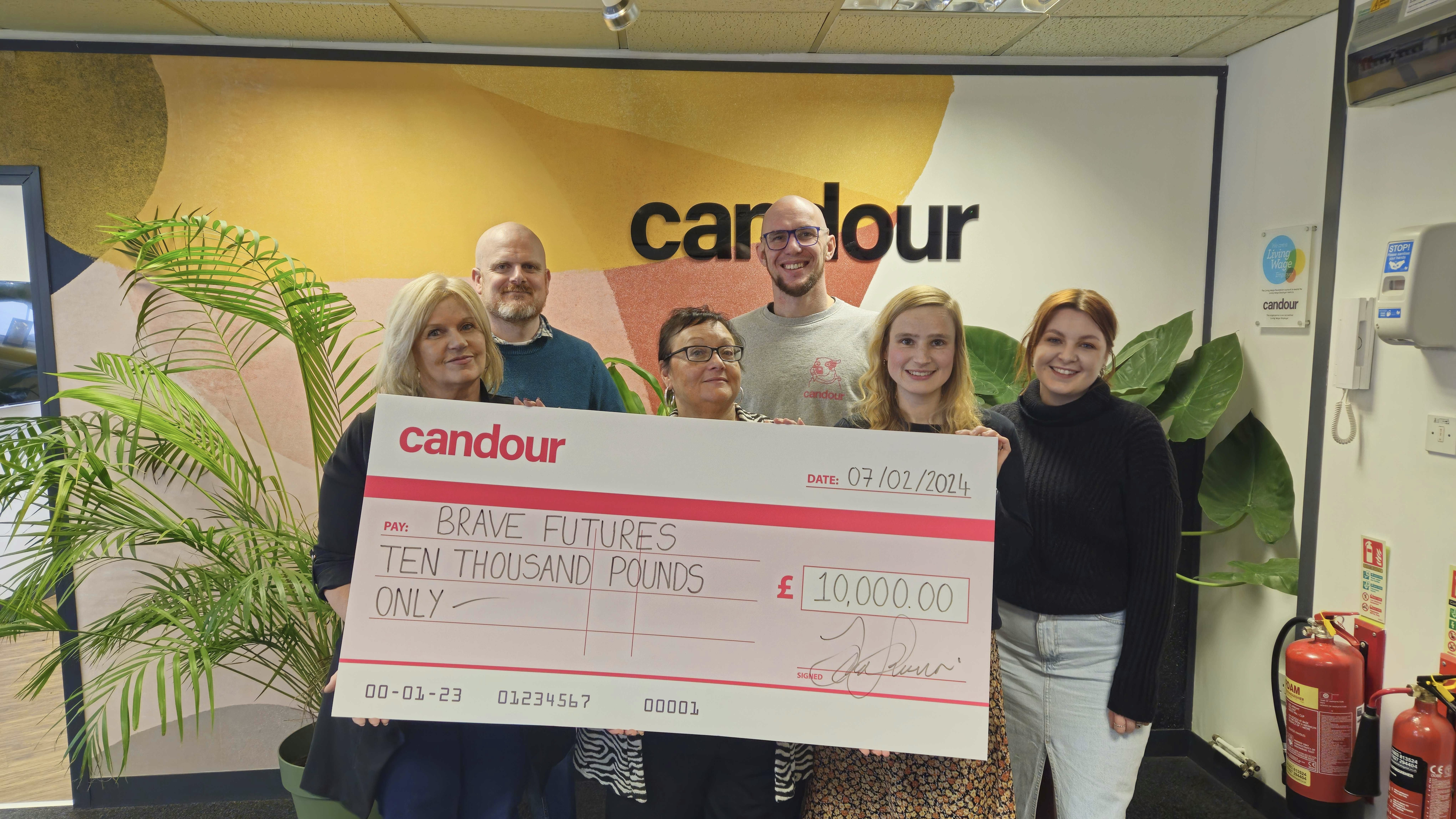 Colleagues from Candour and Brave Futures holding a large cheque for £10,000 which is a donation to Brave Futures