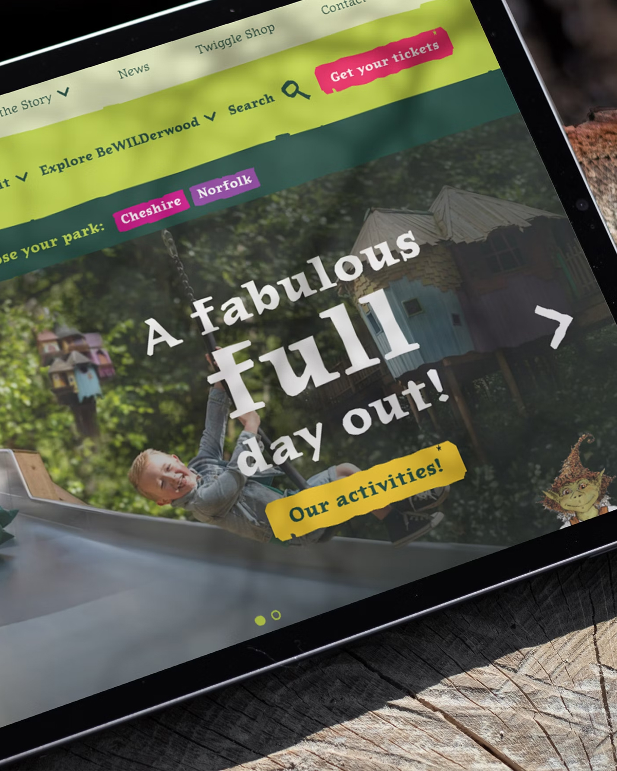 A tablet displaying the BeWILDerwood website, featuring a playful and adventurous design with vibrant colours, whimsical typography, and an invitation to enjoy a 