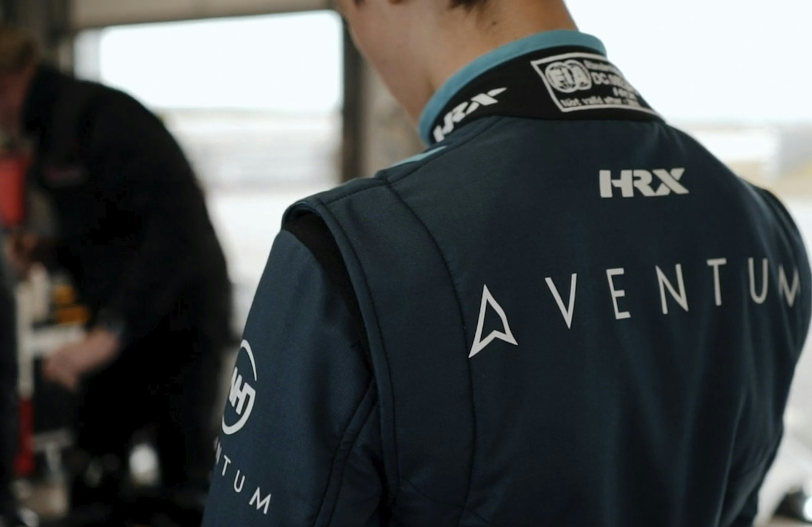 The back view of the racing driver Olly Bearman showing the Aventum logo on the back of his racing suit