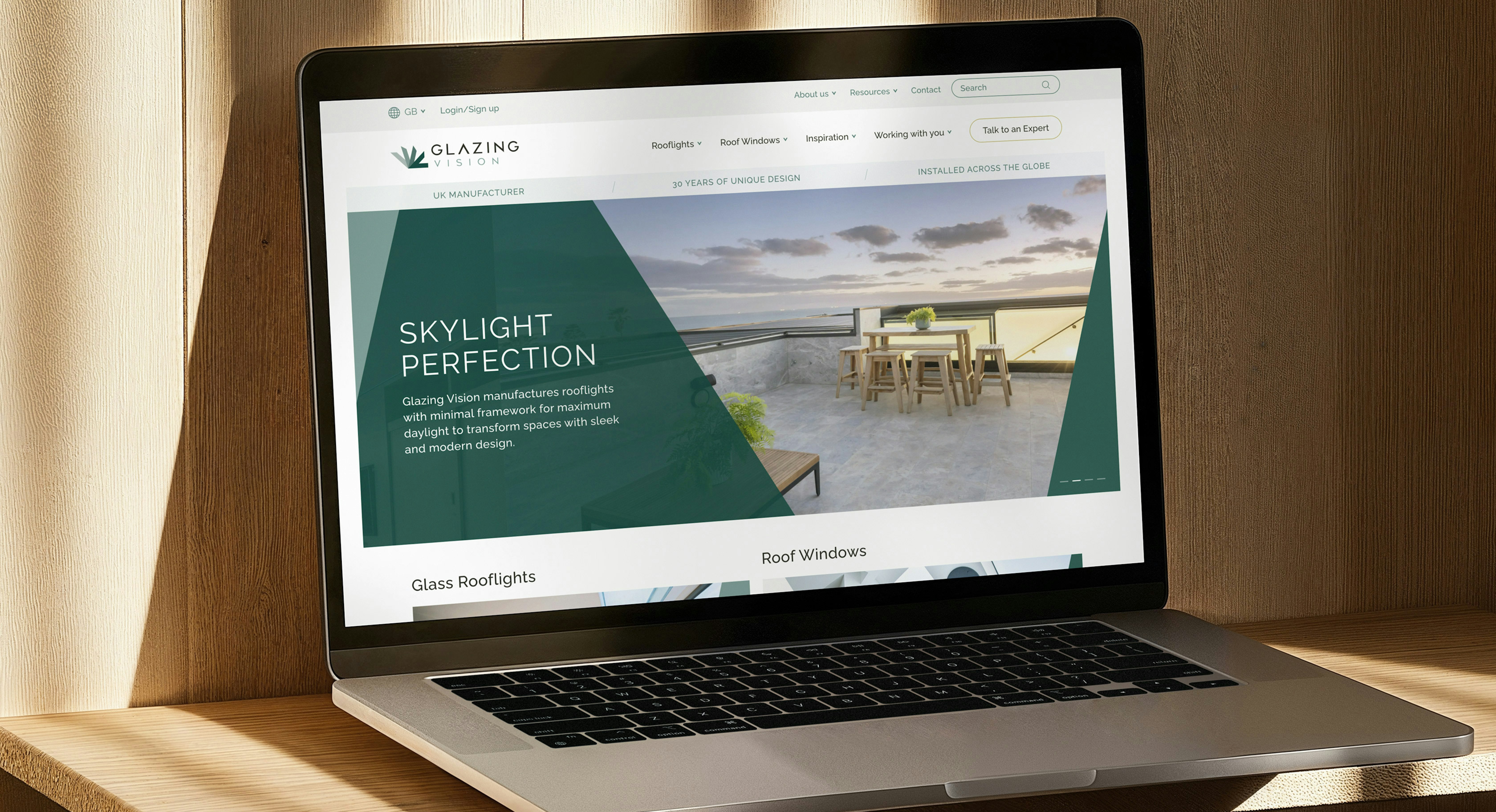 A laptop on a sunny desk position displaying the homepage of the new Glazing Vision website