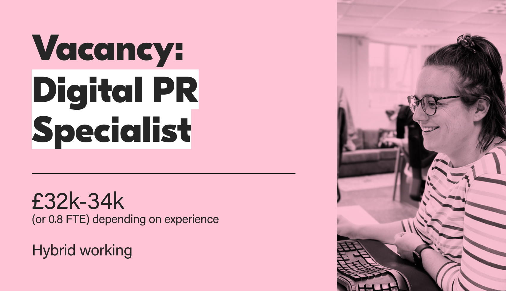 A promotional image for a Digital PR Specialist job vacancy. The left side features large white text on a light pink background announcing: Vacancy: Digital PR Specialist, with the salary range of £32k-34k (or 0.8 FTE depending on experience), and Hybrid working listed below. The right side is a black and white photo of a smiling woman with glasses, wearing a striped top and her hair tied up, sitting at a desk and looking at a computer screen.