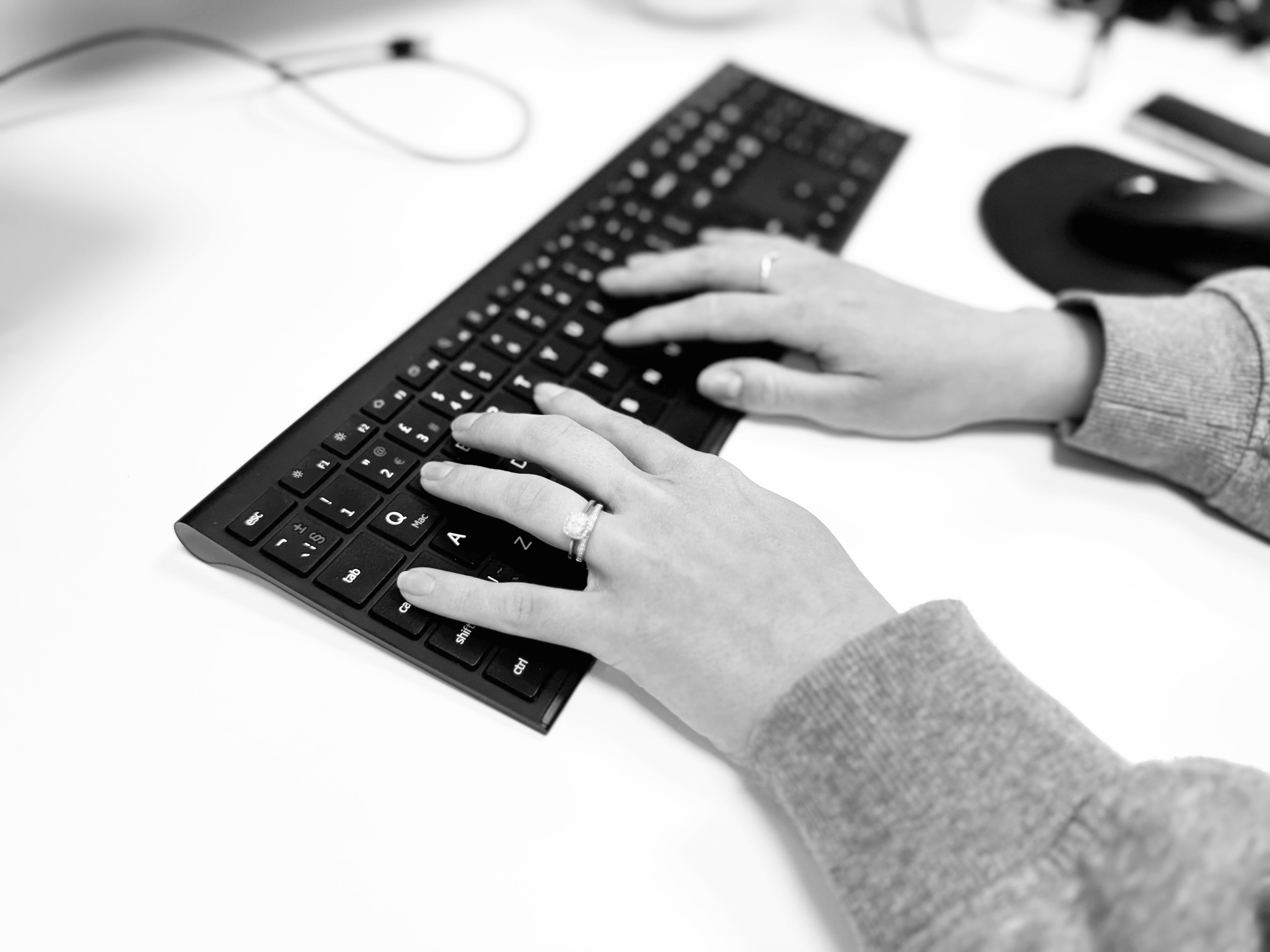 Two hands tapping on a black computer keyboard