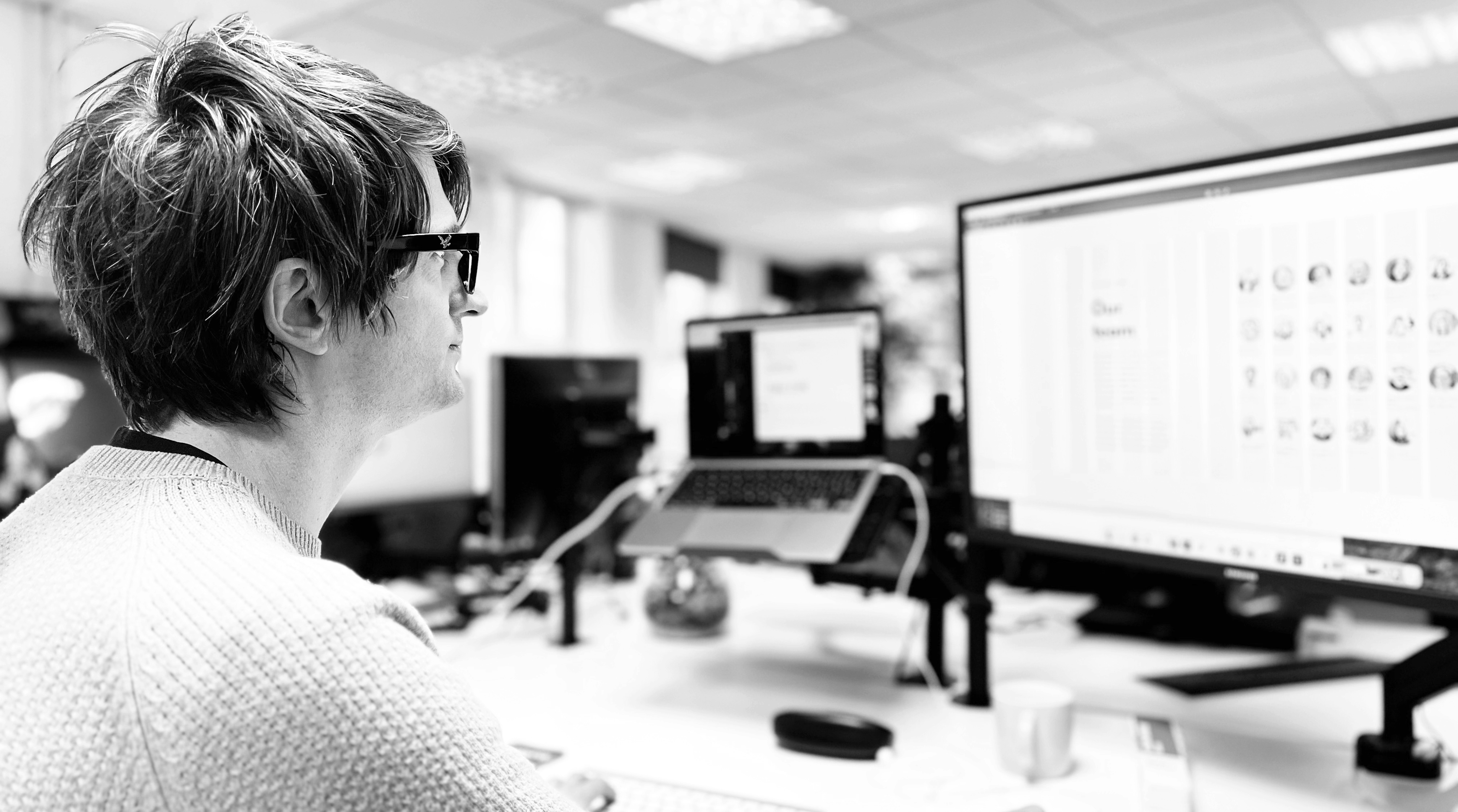 Mark Salisbury at his desk designing a website on a big computer display at Candour Agency